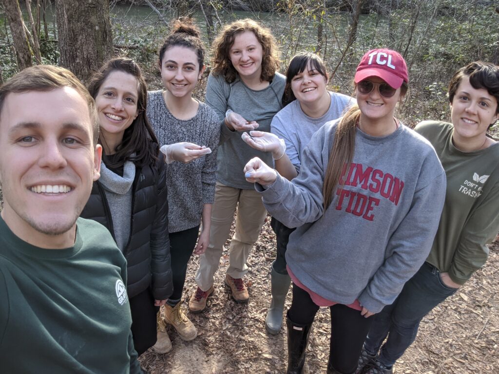 A group of students wearing gloves shows salamanders that they have captured and sampled for disease surveillance.